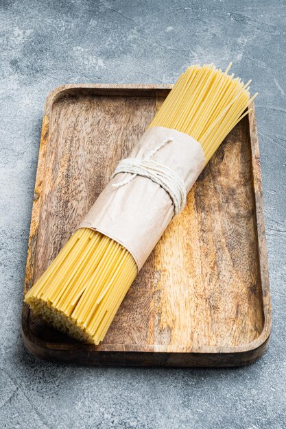 Spaghetti lunghi. Set di spaghetti crudi, su vassoio in legno, su sfondo grigio