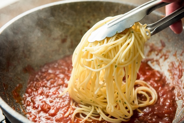 Spaghetti messi nella padella con salsa calda alla bolognese