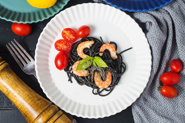 Spaghetti neri con gamberetti sul piatto bianco