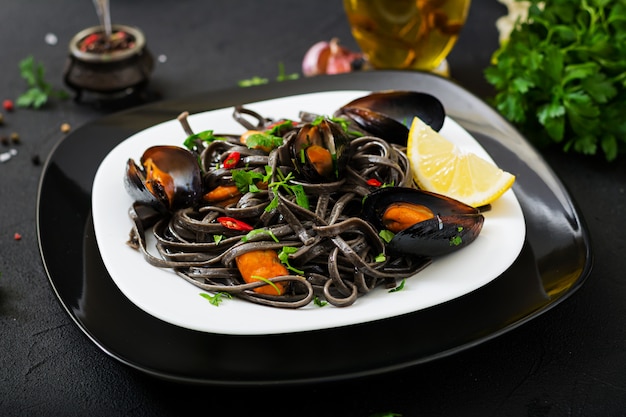 Spaghetti neri. Pasta nera dei frutti di mare con le cozze sopra la tavola nera. Cibo prelibatezza mediterranea