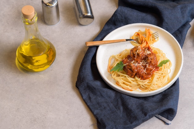 Spaghetti o pasta fatti in casa con polpetta e formaggio in salsa di pomodoro disposti in un piatto bianco.