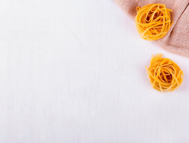 Spaghetti rotondi su tela di sacco e tavola bianca in legno