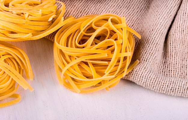 Spaghetti rotondi su tela di sacco e tavolo bianco