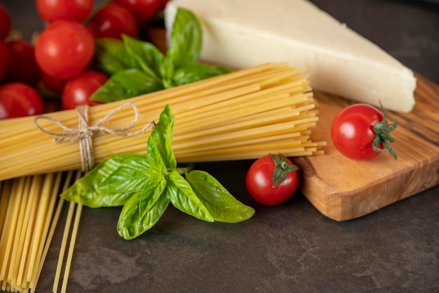 Spaghetti su fondo scuro, formaggio, pomodori e basilico