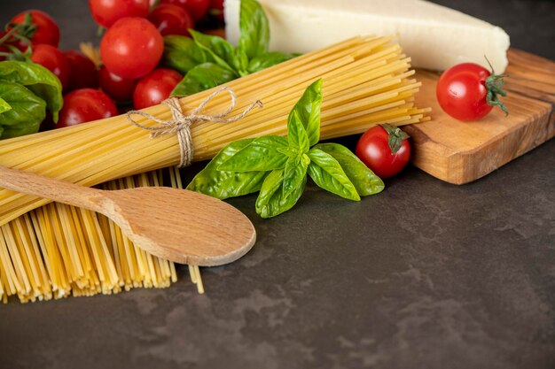 Spaghetti su fondo scuro, formaggio, pomodori e basilico