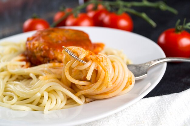 Spaghetti su una forchetta. Pasta con pomodori freschi e polpette di carne