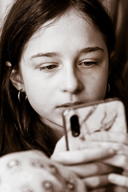 Spalla della ragazza adolescente che esamina lo smartphone Foto in bianco e nero di una ragazza triste