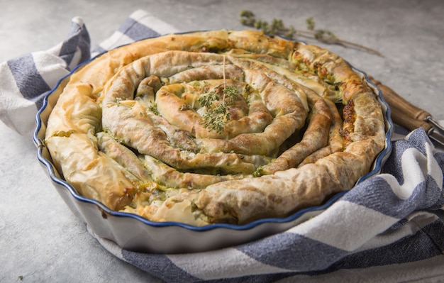 Spanakopita greco della torta sopra fondo concreto. Idee e ricette per la torta di spinaci vegetariana o vegana da pasta fillo tagliata a fette