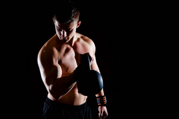 Sparato del giovane muscolare in buona salute che fa esercizio del peso con i dumbbells