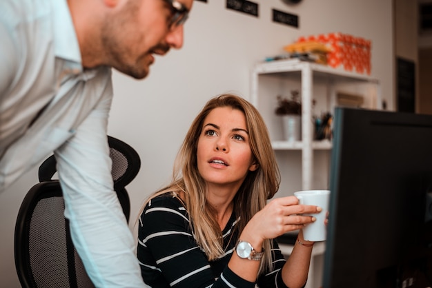 Sparato di due giovani persone di affari felici che godono del lavoro nell&#39;ufficio.