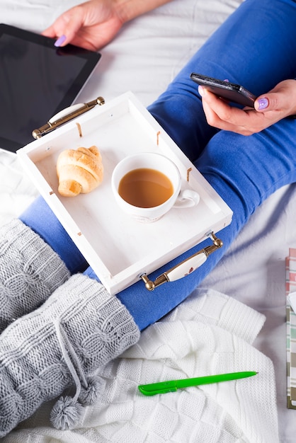 Sparato di una mano femminile che giudica telefono disponibile durante la prima colazione