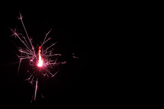 Sparkler che brucia in luce rosa e bianca su sfondo nero Foto del primo piano di Natale e Capodanno sparkler Può essere utilizzato come una carta da parati o una cartolina