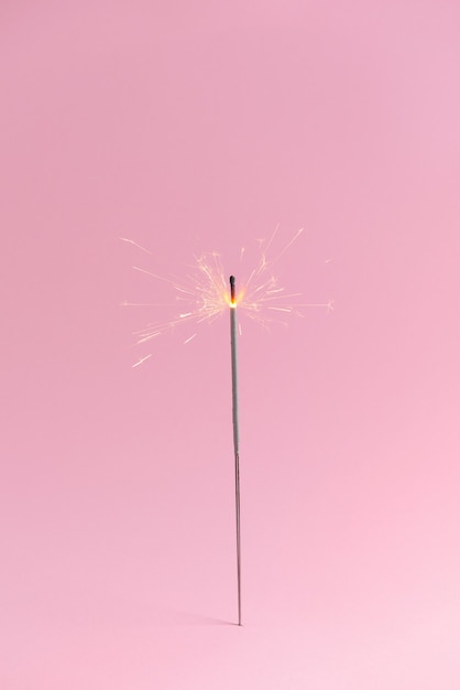 Sparkler festivo su superficie rosa