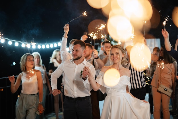 Sparklers al matrimonio degli sposi nelle mani di ospiti gioiosi