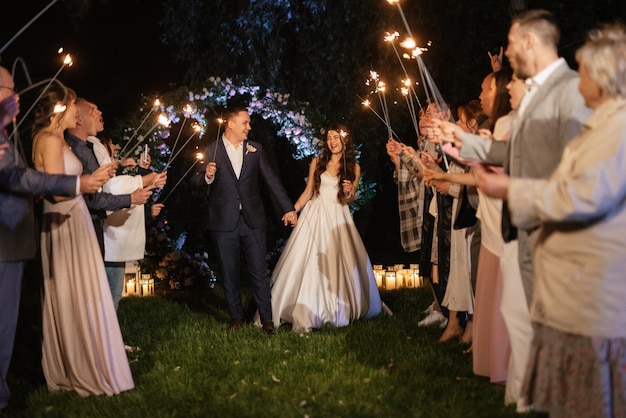 Sparklers al matrimonio degli sposi nelle mani di ospiti gioiosi