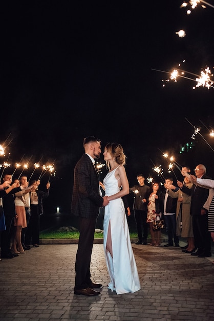 Sparklers al matrimonio degli sposi nelle mani di ospiti gioiosi