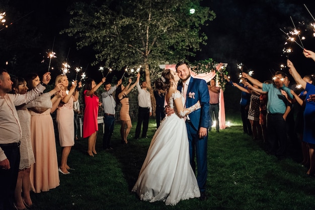 Sparklers al matrimonio degli sposi nelle mani di ospiti gioiosi