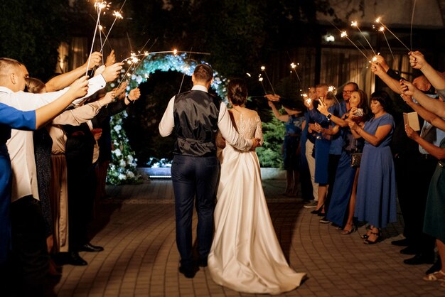 Sparklers al matrimonio degli sposi nelle mani di ospiti gioiosi