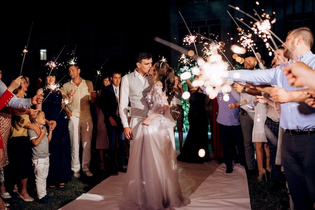 Sparklers al matrimonio degli sposi nelle mani di ospiti gioiosi