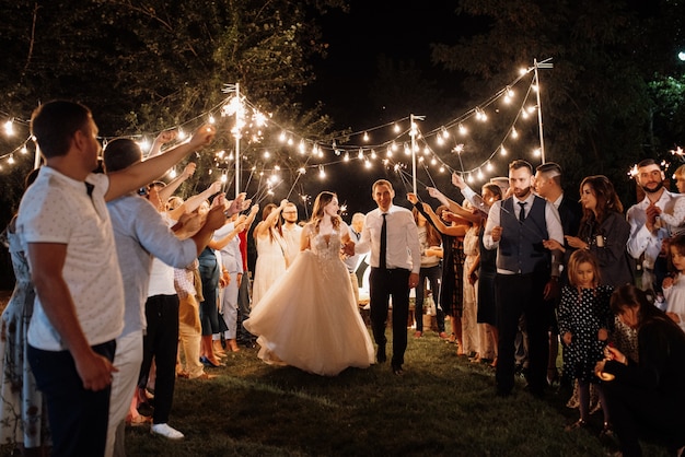 Sparklers al matrimonio degli sposi nelle mani di ospiti gioiosi