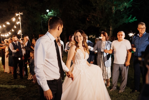 Sparklers al matrimonio degli sposi nelle mani di ospiti gioiosi