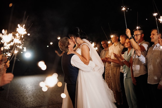 Sparklers al matrimonio degli sposi nelle mani di ospiti gioiosi