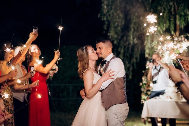 Sparklers al matrimonio degli sposi nelle mani di ospiti gioiosi