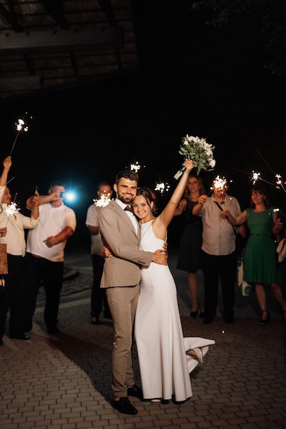 Sparklers al matrimonio degli sposi nelle mani di ospiti gioiosi