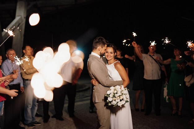 Sparklers al matrimonio degli sposi nelle mani di ospiti gioiosi