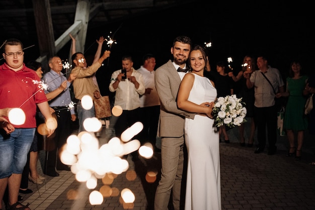 Sparklers al matrimonio degli sposi nelle mani di ospiti gioiosi