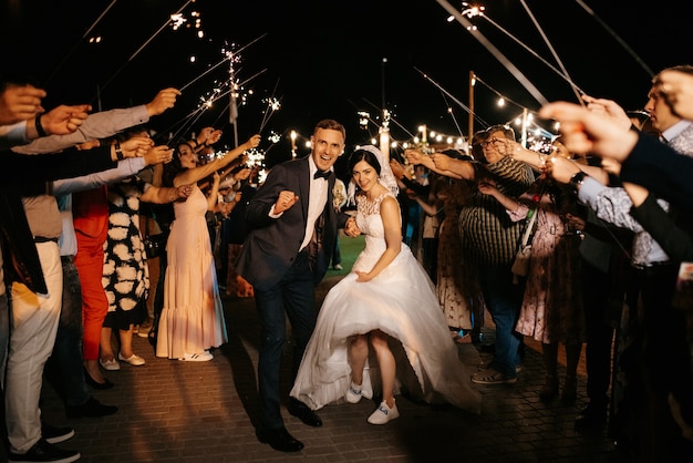 Sparklers al matrimonio degli sposi nelle mani di ospiti gioiosi