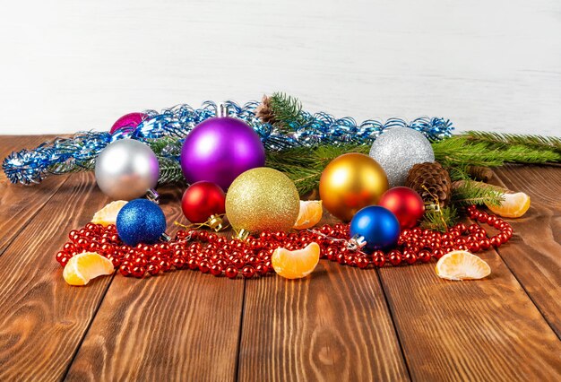 Sparse su un tavolo di legno ci sono decorazioni multicolori per alberi di Natale, coni e mandarino