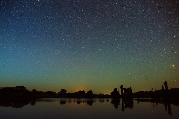 Spazio con le stelle nel cielo notturno Il paesaggio con il fiume e gli alberi su una lunga esposizione