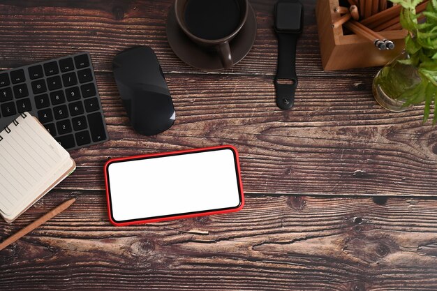 Spazio di lavoro vintage con smart phone, notebook, smart watch, pianta d'appartamento e tazza di caffè sul tavolo di legno.