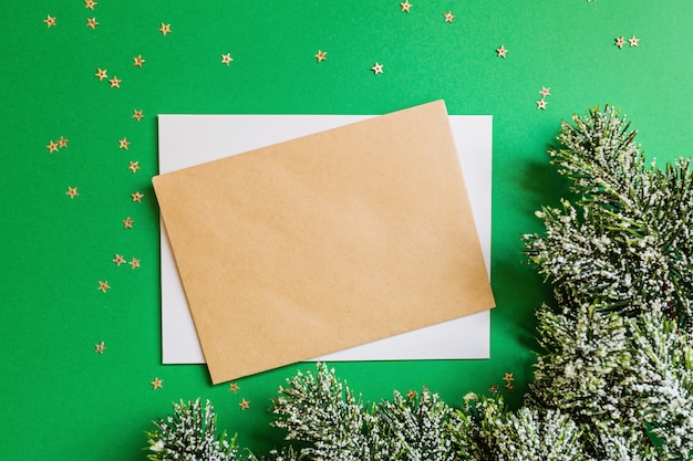 Spazio in bianco di carta, rami dell'albero di Natale su fondo verde con i coriandoli.
