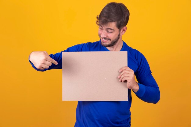 Spazio libero per la pubblicità Felice uomo caucasico che punta al bordo bianco vuoto sul mockup di sfondo giallo dello studio