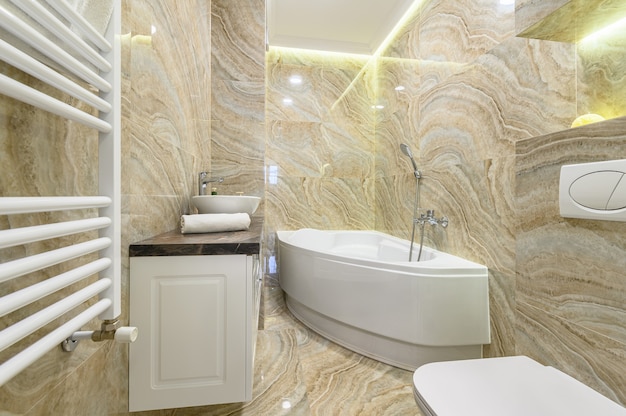 Spazioso bagno di lusso con vasca da bagno bianca e piastrelle in marmo beige