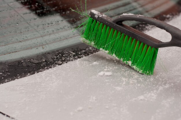 Spazzola per auto verde sullo sfondo di un bagagliaio nella neve