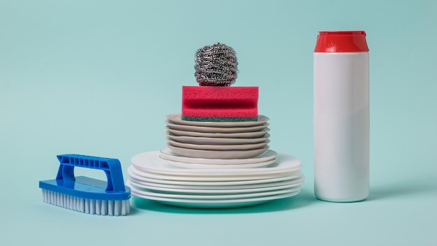 Spazzole per piatti in polvere per la pulizia e un set di piatti bianchi su sfondo blu