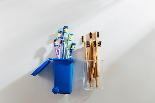 Spazzolini da denti in bambù ecologici in vetro e spazzolini da denti in plastica nel cestino.