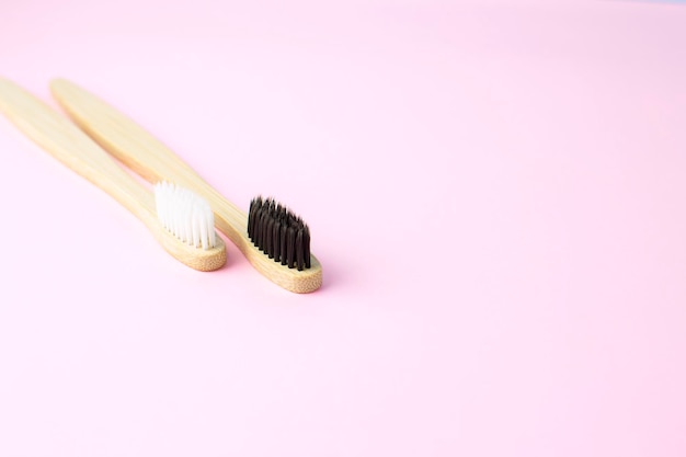 Spazzolini da denti in bambù o legno bianchi e neri su sfondo rosa con spazio per la copia