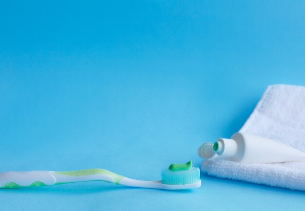 Spazzolino da denti con dentifricio accanto al dentifricio che si trova su un asciugamano bianco.