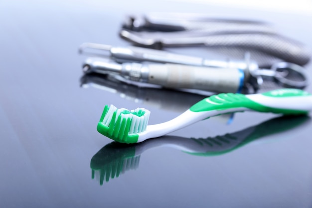 Spazzolino da denti di cure odontoiatriche con gli strumenti del dentista sul fondo dello specchio.