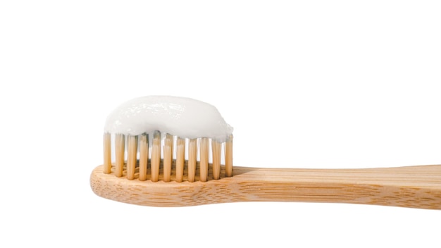 Spazzolino da denti ecologico in legno con dentifricio su sfondo bianco Spazzolina da denti in bambù