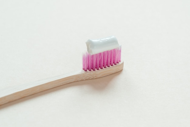 Spazzolino da denti in bambù rosa con dentifricio in primo piano, cure odontoiatriche con concetto di rifiuti zero, stile di vita sostenibile sustainable