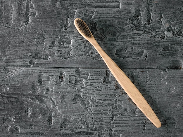 Spazzolino da denti in legno con setole nere sul tavolo di legno scuro. La vista dall'alto.