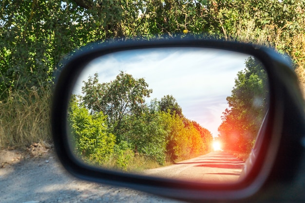 Specchietto retrovisore guida auto vista foresta verde e strada del villaggio