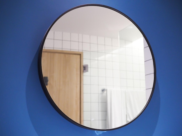 Specchio rotondo in bagno su parete blu con riflessi su vetro