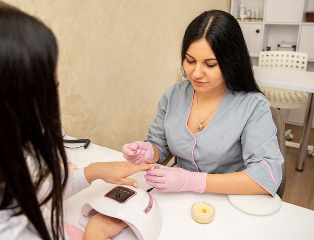 Specialista della giovane donna in manicure che fa massaggio alle mani con crema