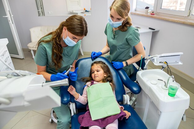 Specialista dentista donna che lava i denti del bambino piccolo che è stato portato alla reception